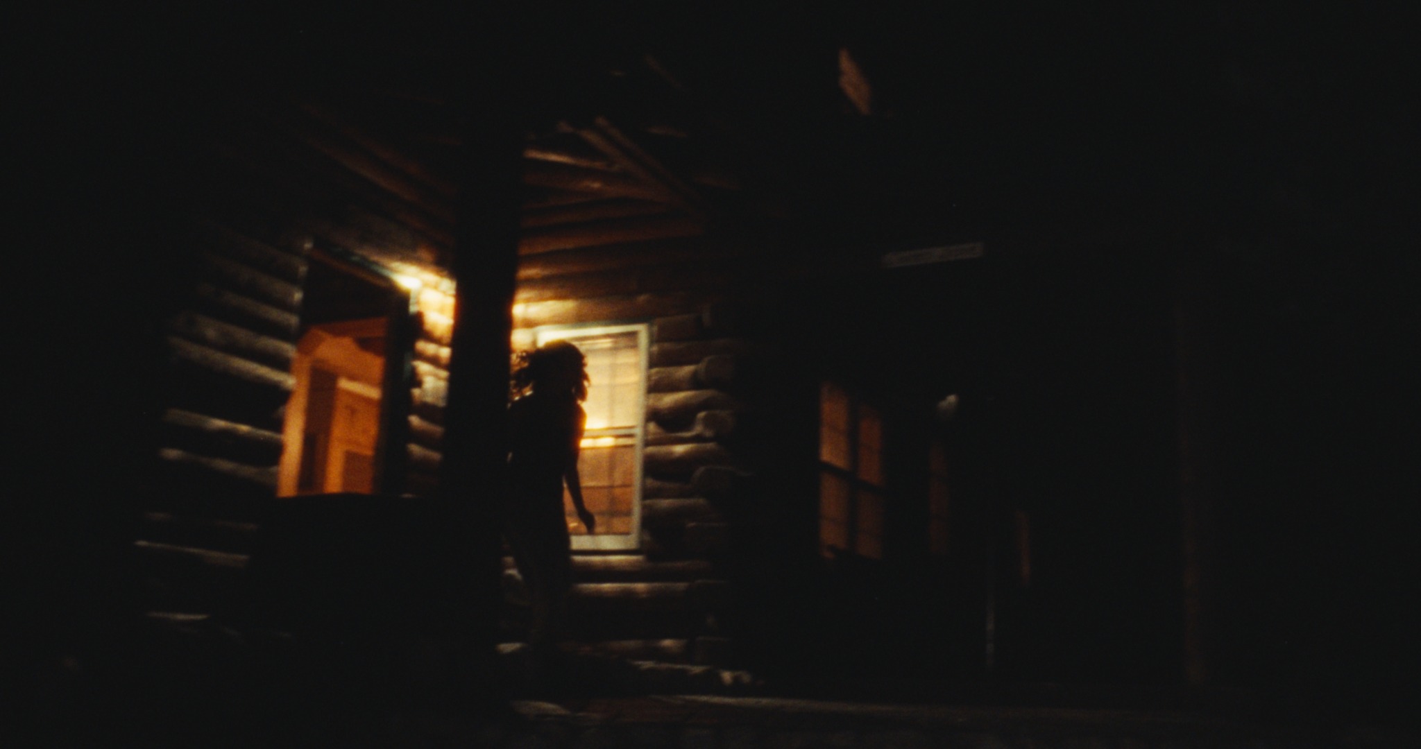 Nighttime scene outside a warmly lit log cabin